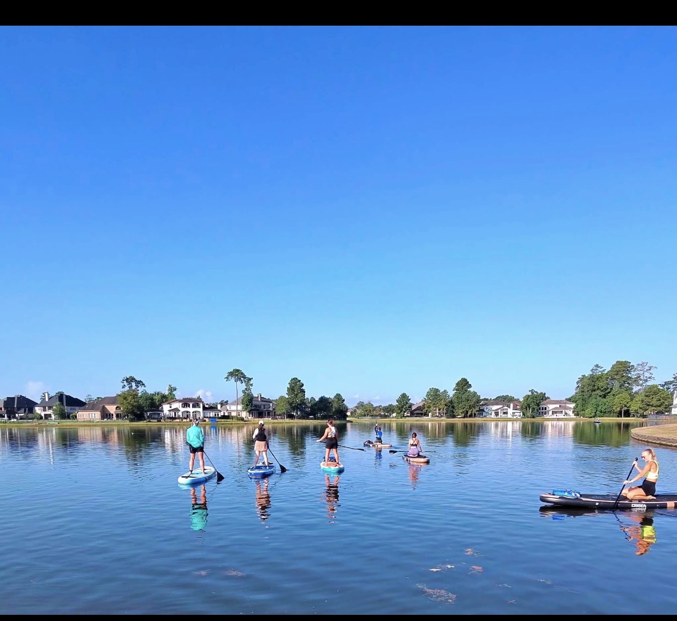 The Generation Zen Paddle Crew paddling together across a calm lake in The Woodlands
