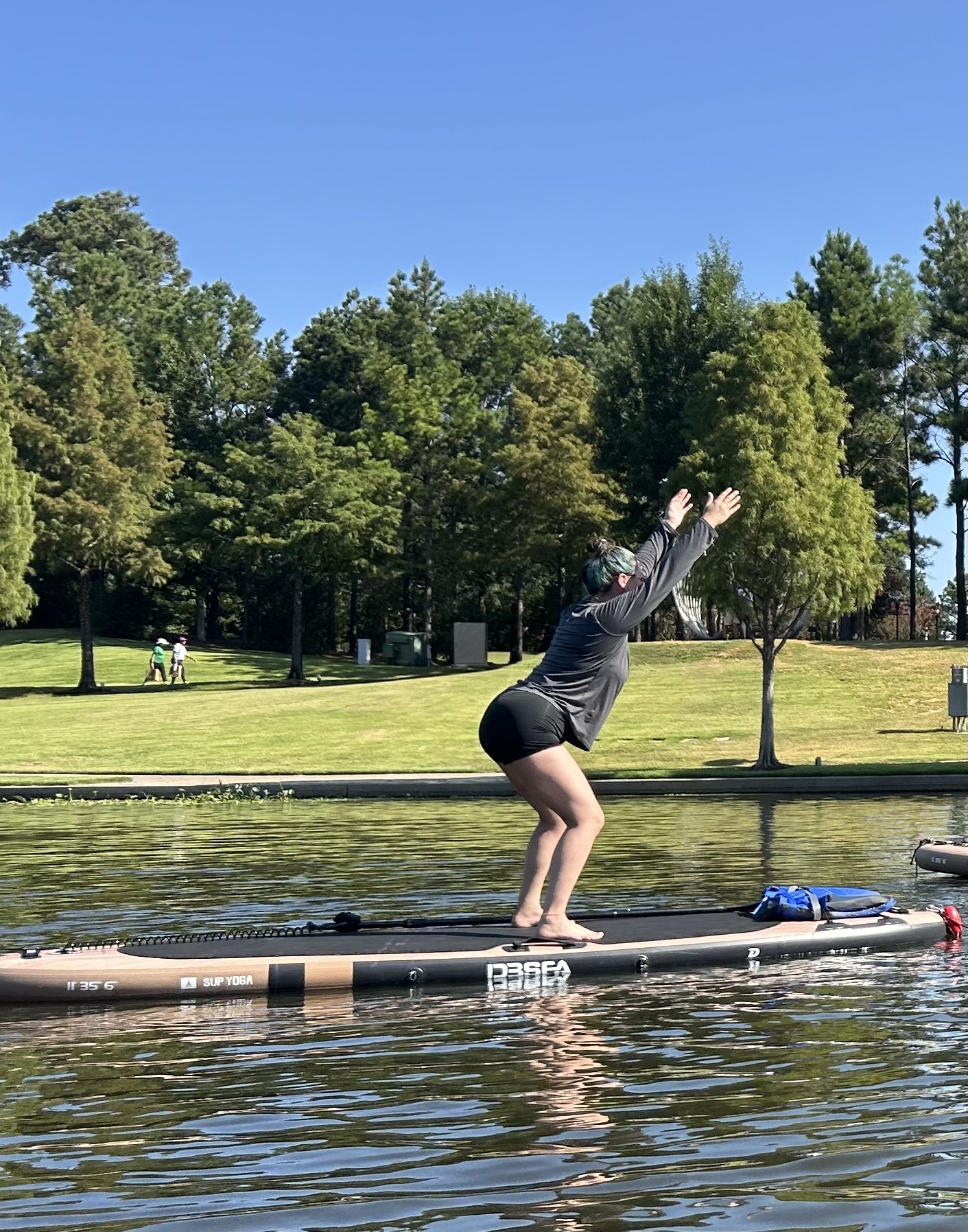 A person balancing in a chair pose on a paddleboard with arms lifted