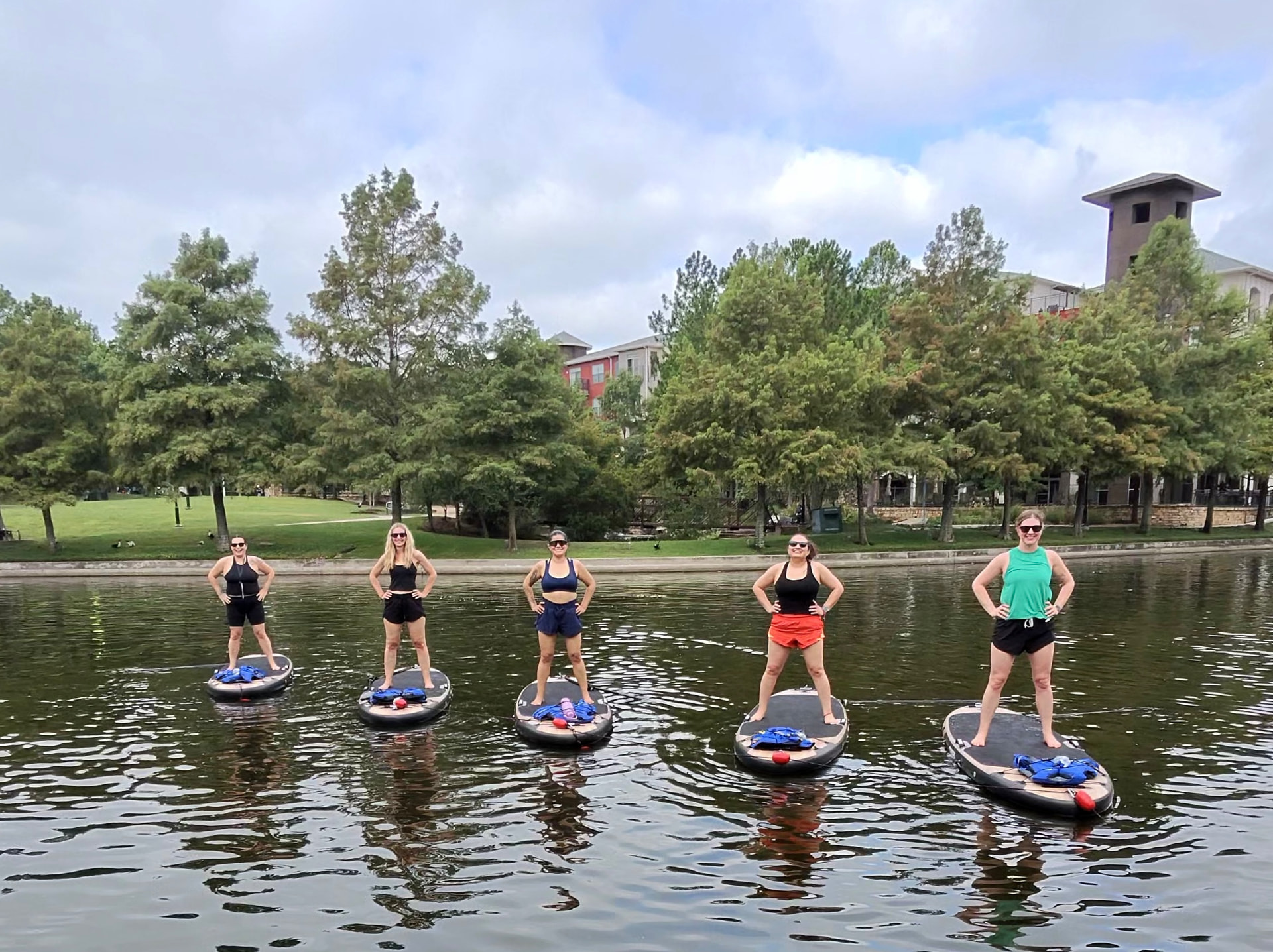Five women standing confidently on paddleboards in a line on the water